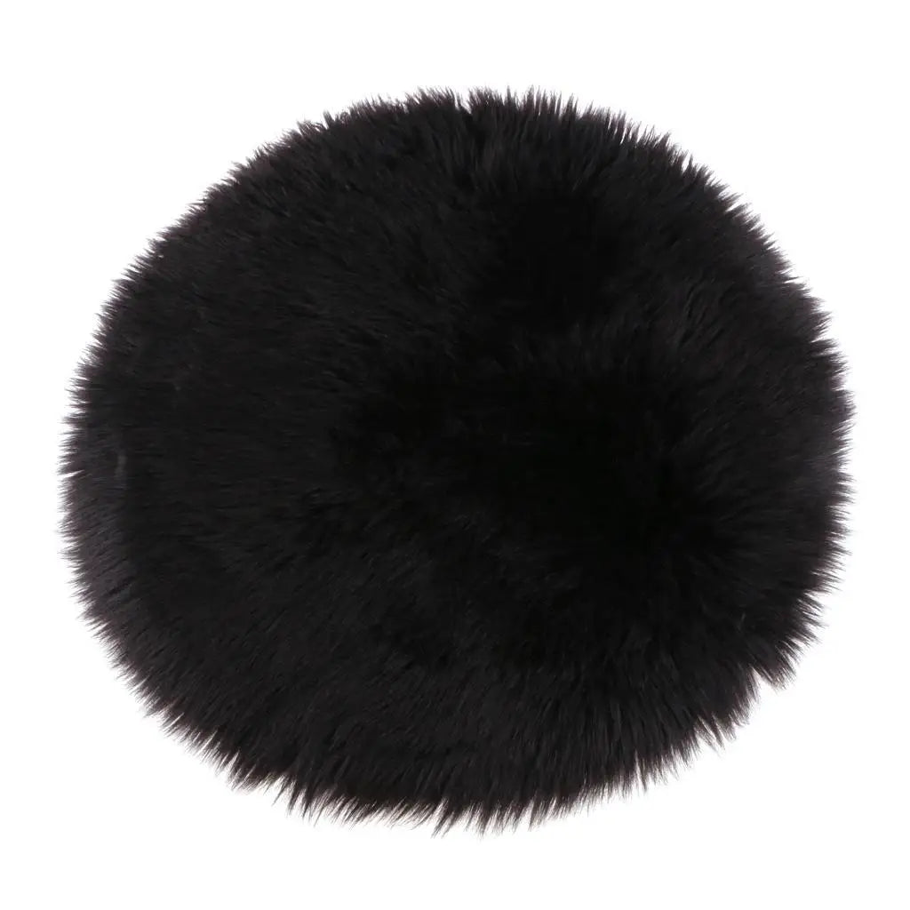 A round black faux fur sheepskin area rug with a plush texture.