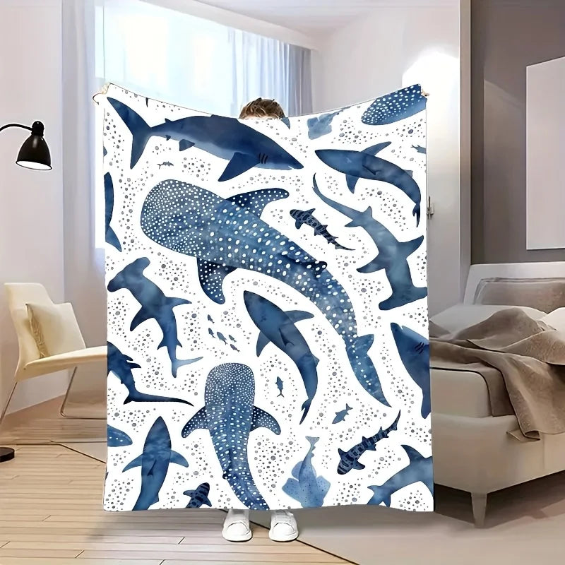 A plush blanket featuring a blue whale shark pattern displayed in a modern bedroom setting.