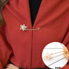 A gold-toned adjustable pearl brooch pinned onto a red coat lapel.