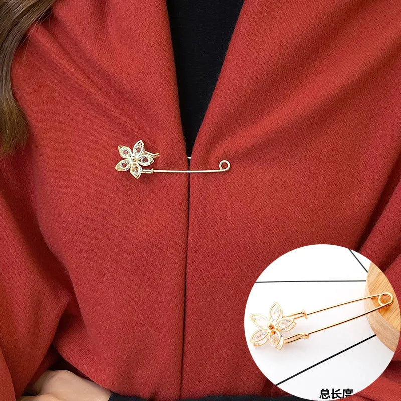 A gold-toned adjustable pearl brooch pinned onto a red coat lapel.