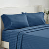 A navy blue striped bedding set featuring a duvet cover and pillows on a white upholstered bed.