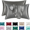 A set of satin pillowcases in various shades including gray, green, purple, and white.