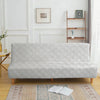 A light gray velvet non-slip armless sofa cover displayed on a wooden floor with a patterned rug.