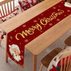 A festive red table runner with gold glitter text reads Merry Christmas and features scattered gold snowflakes on a wooden ta