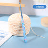A blue ergonomic crochet hook with a floral design is shown next to a ball of light-colored yarn.