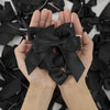 A pair of hands holding a black satin ribbon twist tie bow