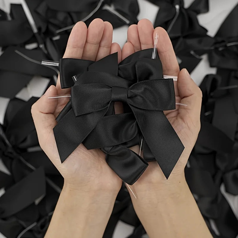 A pair of hands holding a black satin ribbon twist tie bow