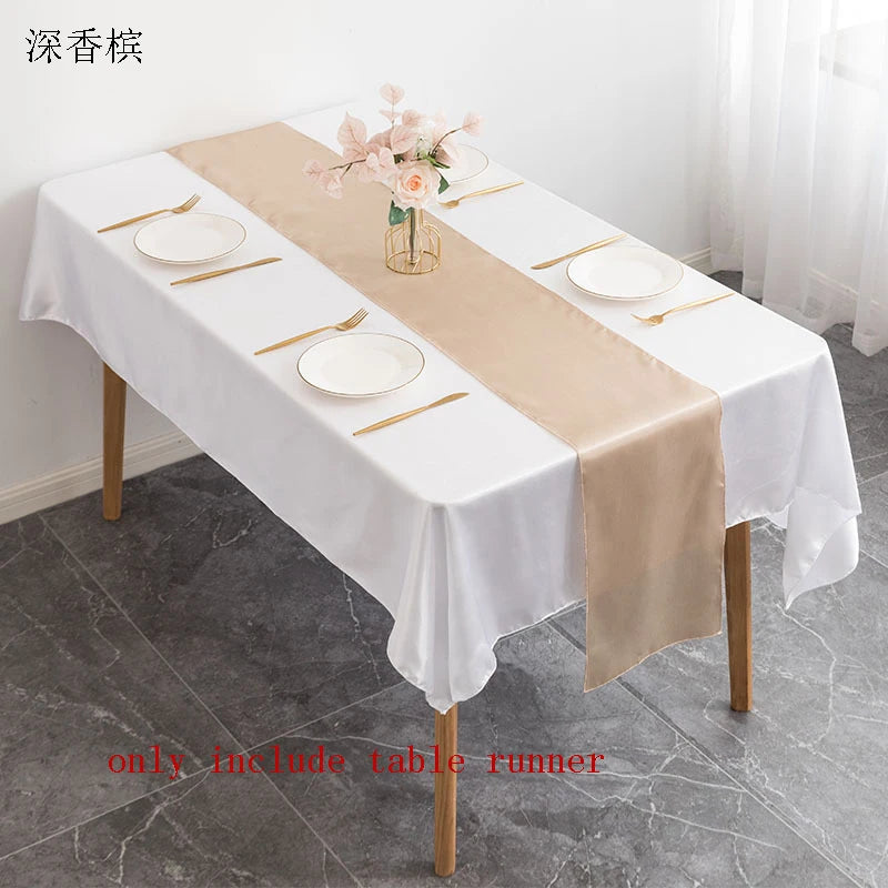 A long satin beige table runner is displayed on a white tablecloth set for an elegant dining or event.