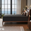 A dark gray hybrid memory foam and pocket spring mattress resting on a wooden bed frame in a modern bedroom.