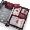 A set of six dark red and gray travel packing cubes inside a black suitcase.