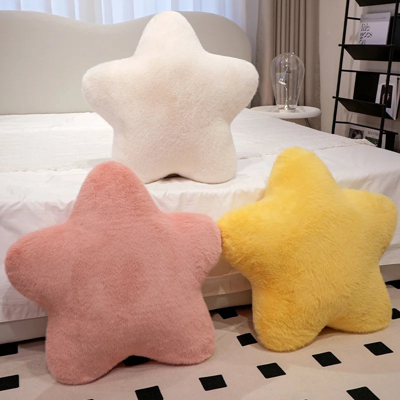 A collection of star-shaped decorative throw pillows in pink and yellow resting on a white bed.