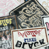 A collection of embroidered iron-on clothing patches featuring various text designs and distressed textures.