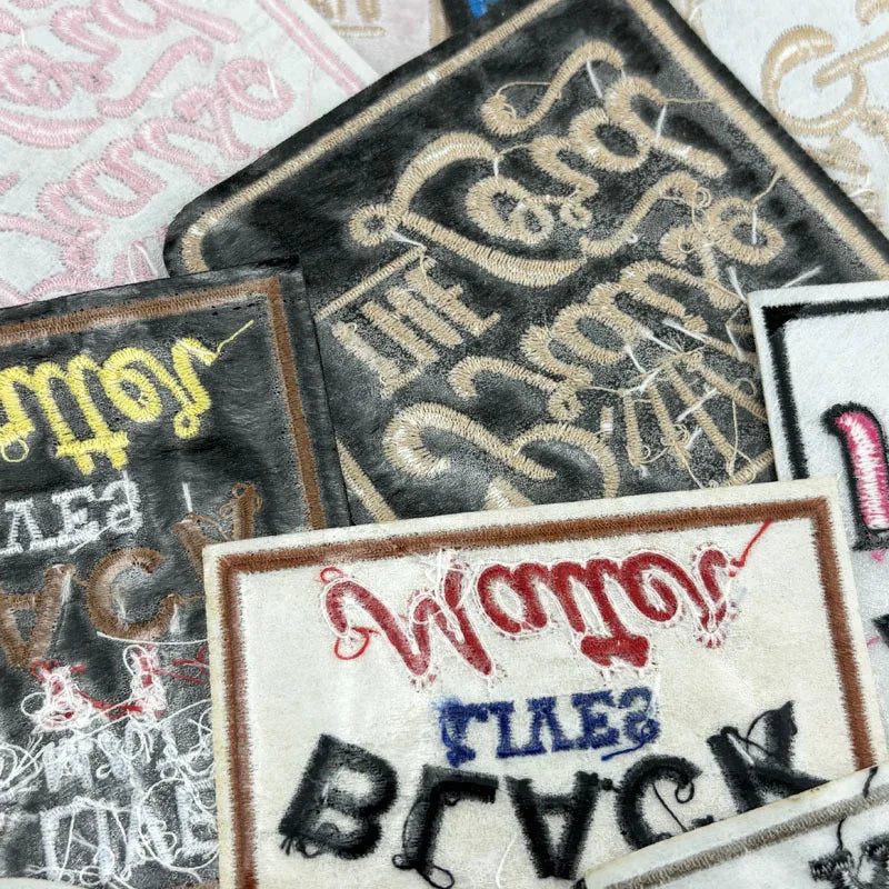 A collection of embroidered iron-on clothing patches featuring various text designs and distressed textures.