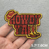 An embroidered patch featuring the text HOWDY YALL in a western style with a cowboy hat design.
