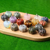 A collection of handcrafted natural stone pumpkin figurines in various shades of green, pink, yellow, and gray displayed on a