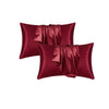 Two deep burgundy satin silk pillow covers folded and displayed