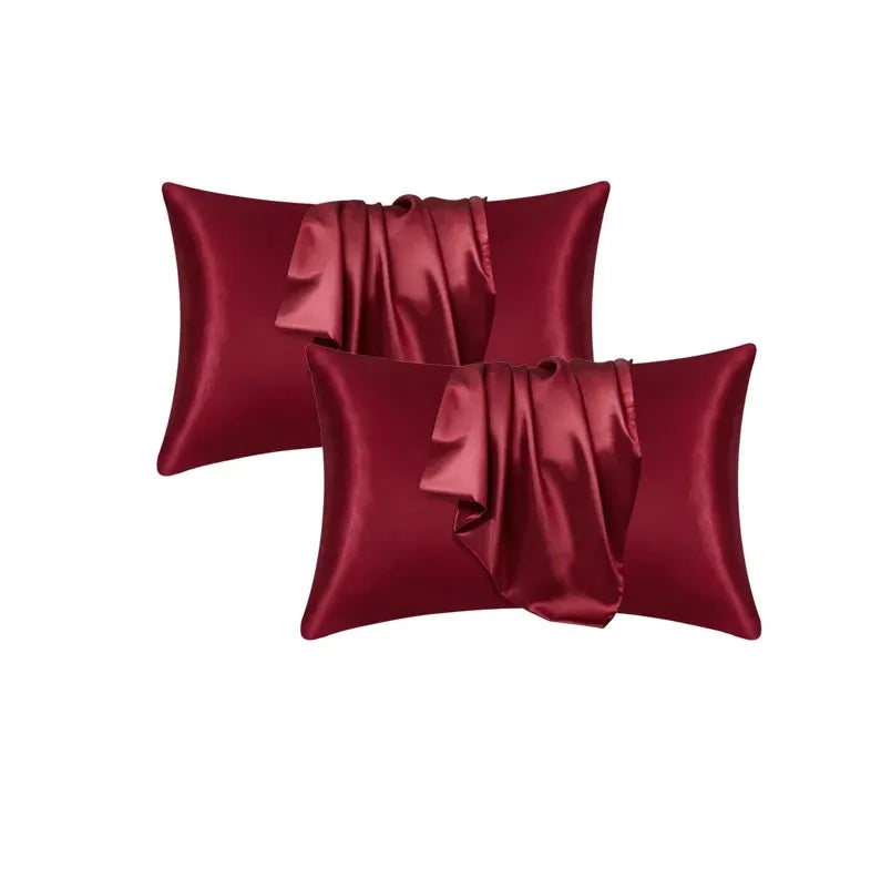 Two deep burgundy satin silk pillow covers folded and displayed