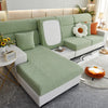 A light green jacquard elastic sofa slipcover with white accents and pillows in a modern living room setting.