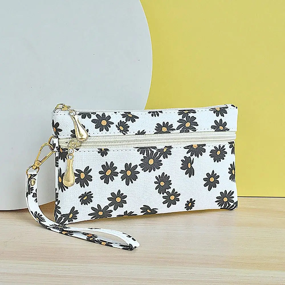 White PU leather coin purse with a floral pattern and a gold-toned wrist strap against a yellow background.