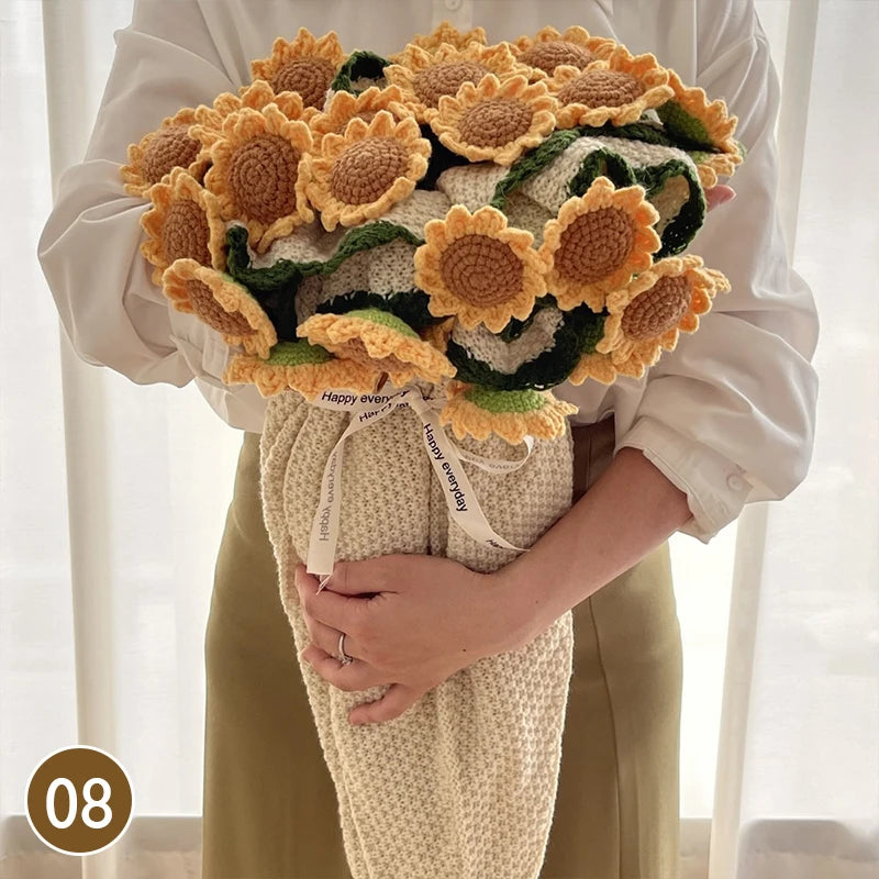 A hand knitted floral rose bouquet arrangement wrapped in a beige throw blanket, held by a person.