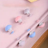 A collection of no-sew silicone quilt clips in various pastel colors including pink, purple, and blue, displayed on a pink fa