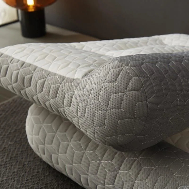A stack of light gray quilted ergonomic contour pillows for neck and spine support.