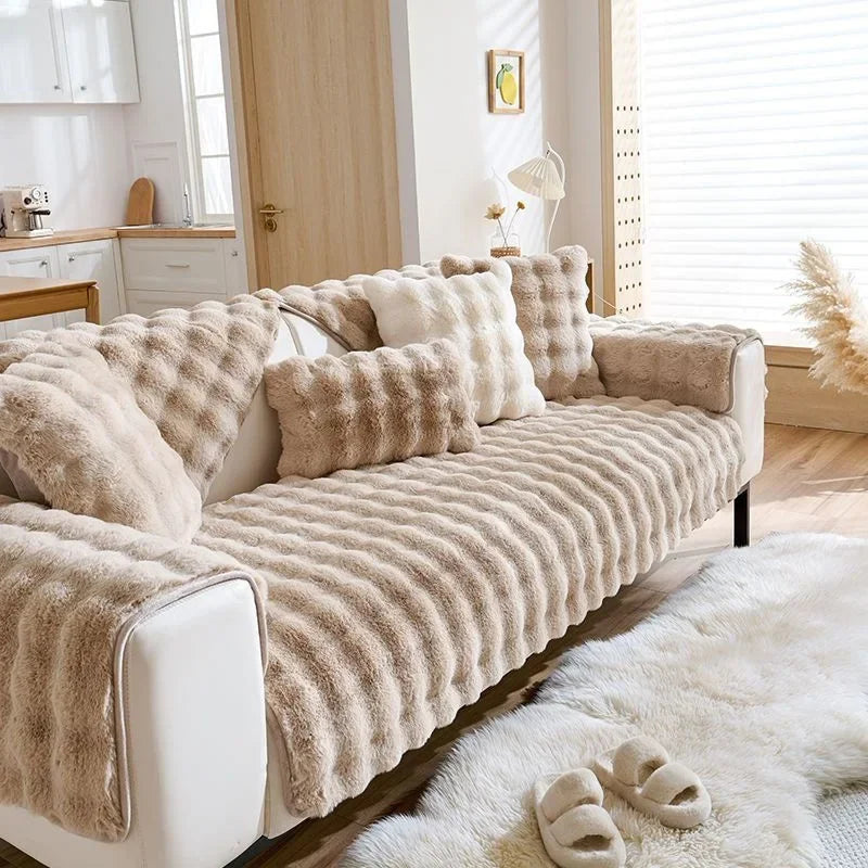 A beige plush rabbit sofa cushion on a white sofa with a fluffy white rug.