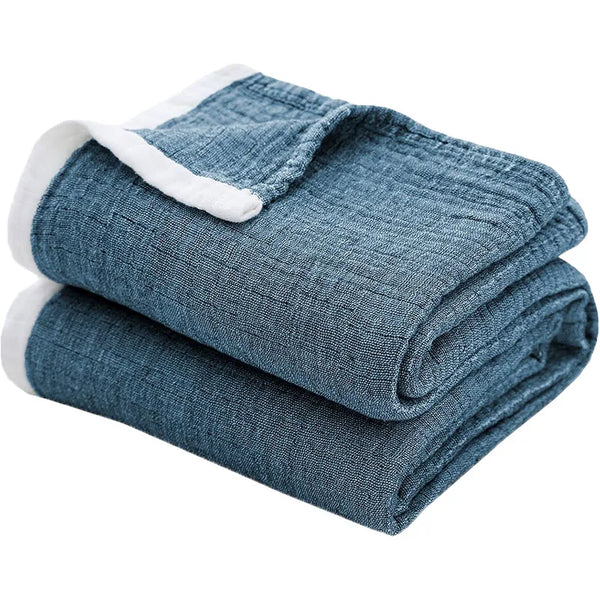 A folded blue muslin throw blanket with white trim.
