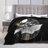 A black microfiber throw blanket featuring a large crescent moon and silhouette design on a light gray bed.