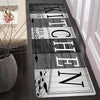 A long, rectangular kitchen mat with the word 'ITCHEN' written in various fonts and styles on a dark background.