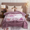 A purple weighted blanket with floral patterns is displayed on a bed and a nearby bedside lamp.