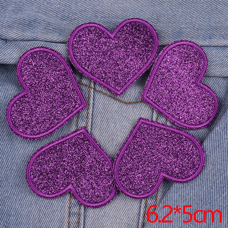Five purple glitter iron-on embroidered love heart star patches arranged in a circle on denim fabric.
