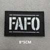 Black embroidered patch with white text FAFO on a gray background