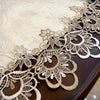 Elegant lace trim on a beige tablecloth draped over a dark wooden table.