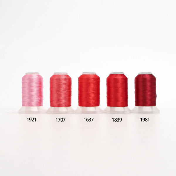 A row of six spools of red and pink embroidery thread with corresponding numbers labeled below them.