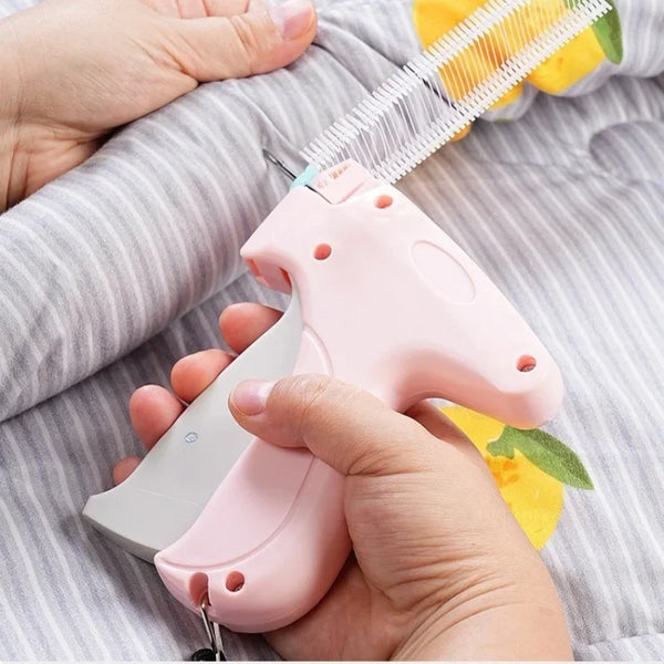 A hand is holding a pink silicone sewing gun with a white needle, positioned over gray fabric.