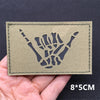 A rectangular olive green fabric patch featuring a black silhouette of a clenched fist.
