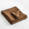 A stack of three folded brown French stone washed linen sheets or towels.
