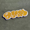 A decorative floor mat shaped like a smiling face in yellow and white embroidery on a green surface.