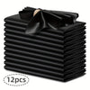 A stack of twelve black silky satin dinner napkins with a decorative bow on top.
