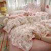 Pink floral bedding set with ruffled duvet and pillows on a bed.