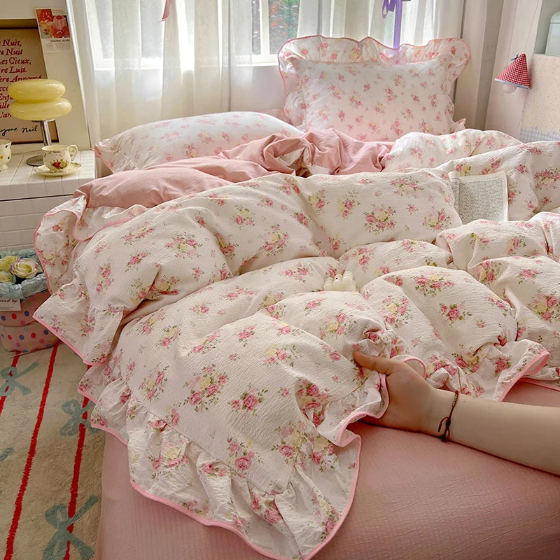 Pink floral bedding set with ruffled duvet and pillows on a bed.