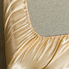 Close-up of a luxurious satin bedding set in a golden beige color showing the smooth fabric texture.