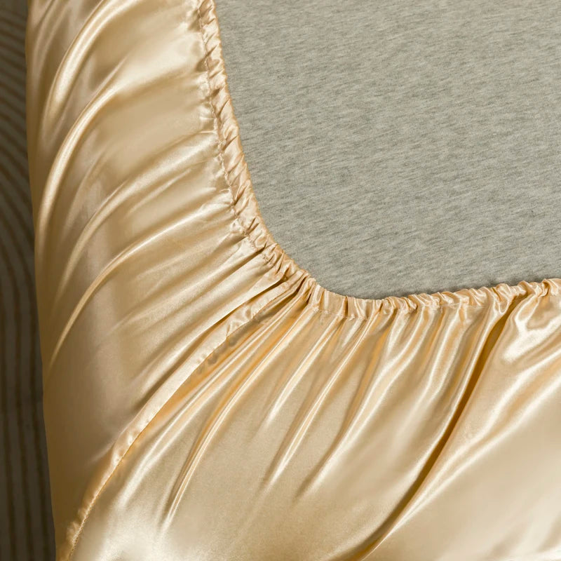 Close-up of a luxurious satin bedding set in a golden beige color showing the smooth fabric texture.