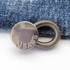 Silver extender buttons for jeans and clothing attached to a denim fabric background