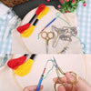 A hand holds vintage stainless steel sewing scissors and embroidery thread on a light fabric background.