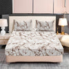 A bed dressed with a white marble print fitted sheet set and matching pillowcases on a light pink upholstered bed frame.