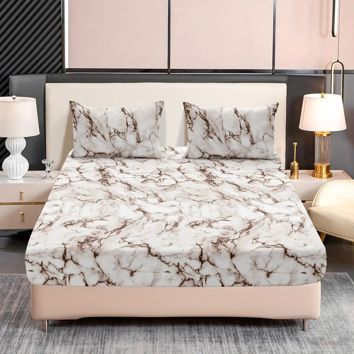 A bed dressed with a white marble print fitted sheet set and matching pillowcases on a light pink upholstered bed frame.