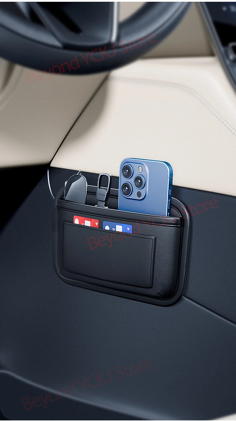 A blue smartphone is stored in a black universal car organizer storage bag placed on a car dashboard.