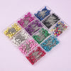 A collection of colorful pearl head sewing pins in various shades and styles arranged in small clear plastic trays.